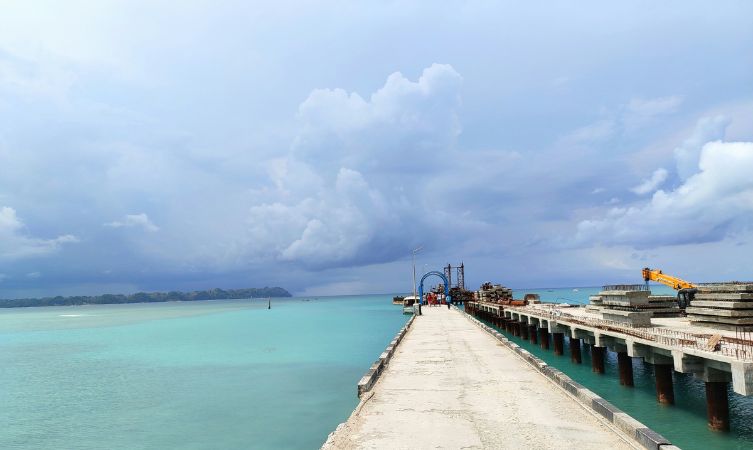 brown wooden dock on sea under white clouds and blue sky during daytime