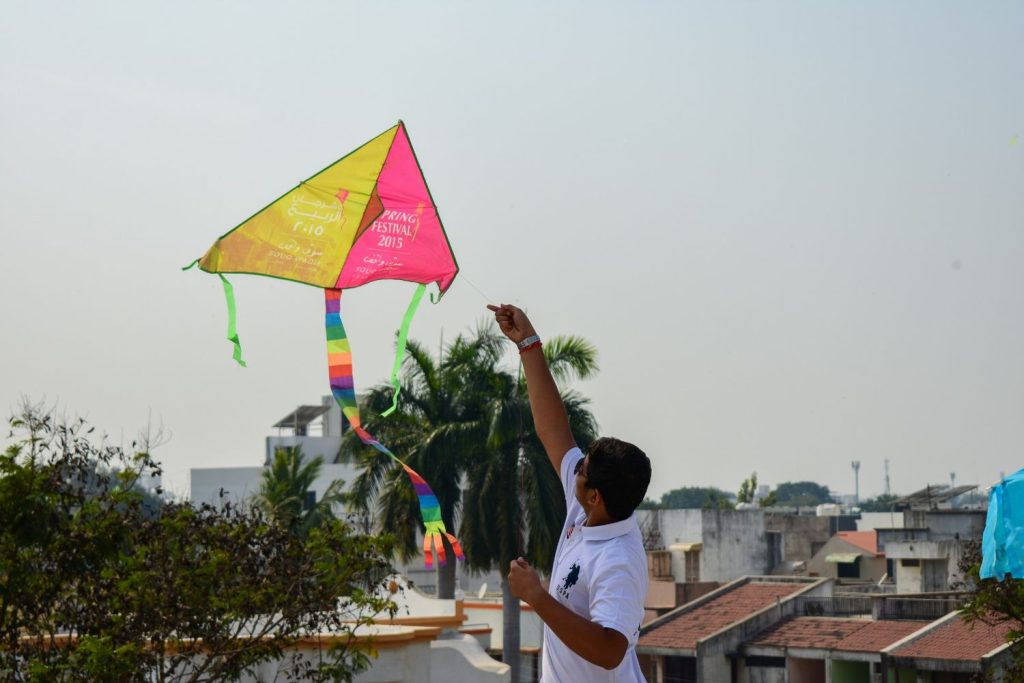 man in white t-shirt holding yellow and red flag